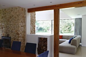 View across dining table and half-height firewood store into lounge area