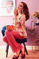 A young woman sitting on a chair with a cigarette and a glass ashtray