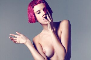 A young topless woman with pink hair
