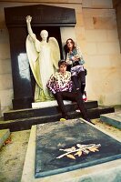 A young couple by a grave in front of an angel's statue
