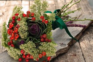 Autumnal flower arrangement with rose hips on wooden table