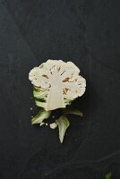 Half a cauliflower floret on a black slate surface