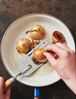 Beef stock being made: halved onions being roasted in a pan