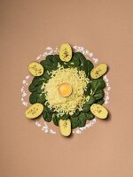 Potatoes, spinach and egg yolk arranged in a circle on a brown surface