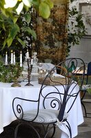 Ornate metal chair at table festively set with white tablecloth