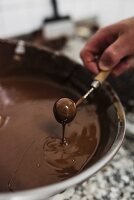 A praline being dipped into liquid chocolate
