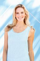 Junge blonde Frau in hell blauem Stricktop