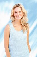 Junge blonde Frau in hell blauem Stricktop