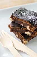 Three brownies with nuts next to wooden cutlery