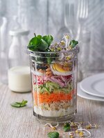 Layered watercress and raw vegetable salad with tender wheat in a jar