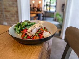 Breaded fish fillet on a bed of vegetables in a restaurant