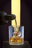 Whisky being poured into a glass of ice