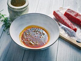 Marinade in einer Schüssel, daneben angefrorenes Fleisch