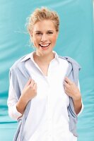 Junge blonde Frau in weisser Bluse mit Pulli um Schultern