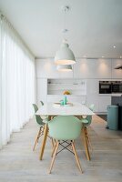 weiße Designerküche mit Essplatz und mintgrünen Schalenstühlen