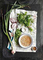 Chickpeas, parsley, onions and garlic on a piece of newspaper