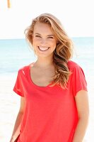A blonde woman wearing a red top on the beach