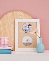 A blue vase next to framed photos with a homemade wooden passepartout