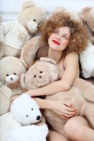 Junge Frau sitzt inmitten von vielen Teddybären