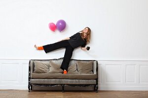 Junge Frau steht auf einem Bein auf altem Sofa