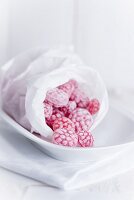 Raspberry sweets in a bread bag on a white dish