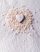 A heart-shaped biscuit with curls of white chocolate on a piece of white paper