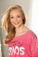A young blonde woman wearing a pink printed T-shirt
