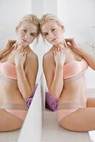 A woman wearing underwear in front of a mirror in a bathroom