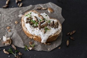A slice of baguette topped with cream cheese, cress and crickets