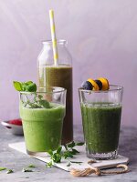 Three green smoothies garnished with chickweed and skewers