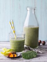 Two green smoothies garnished with turmeric and hazelnuts