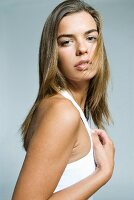 A dark blonde woman wearing a white top