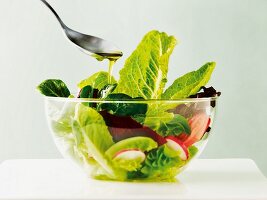 A mixed leaf salad with radishes, tomatoes and olive oil