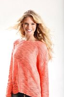 A young blonde woman wearing a knitted salmon coloured jumper