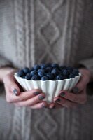 Frau hält Schälchen mit frischen Heidelbeeren in den Händen