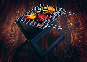 Food on a folding grill on a dark wooden surface