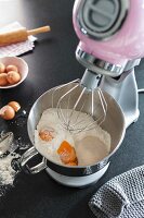 A food processor and a stainless steel mixing bowl with baking ingredients
