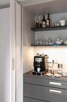 An open sliding door and a view of a kitchen cupboard with an espresso machine