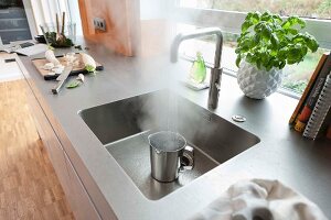 A stainless steel work surface with an integrated sink and a tap with a hot water function