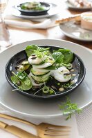 Gedeck mit Spinat-Rettich-Salat und Misodressing auf schwarzem Teller