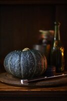 A green pumpkin on a wooden plate