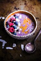 A smoothie bowl with oats, chia seeds, grated coconut, almond butter and blueberry compote