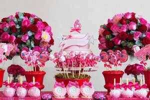 Various cake pops, sweets and birthday cakes between bunches of roses
