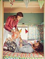 A hippie-style couple having a pillow fight in a caravan