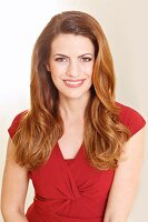 A smiling brunette woman in a red summer dress