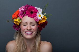 Junge blonde Frau mit buntem Blumenkranz auf dem Kopf