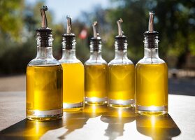 Olive oil in bottles with pourers on an outdoor table