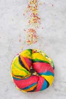 A colourful bagel with cream cheese and sprinkles
