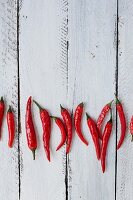 Mehrere frische rote Chilischoten auf weißem Holzuntergrund