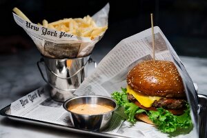 Cheeseburger mit Pommes Frites auf Zeitungspapier